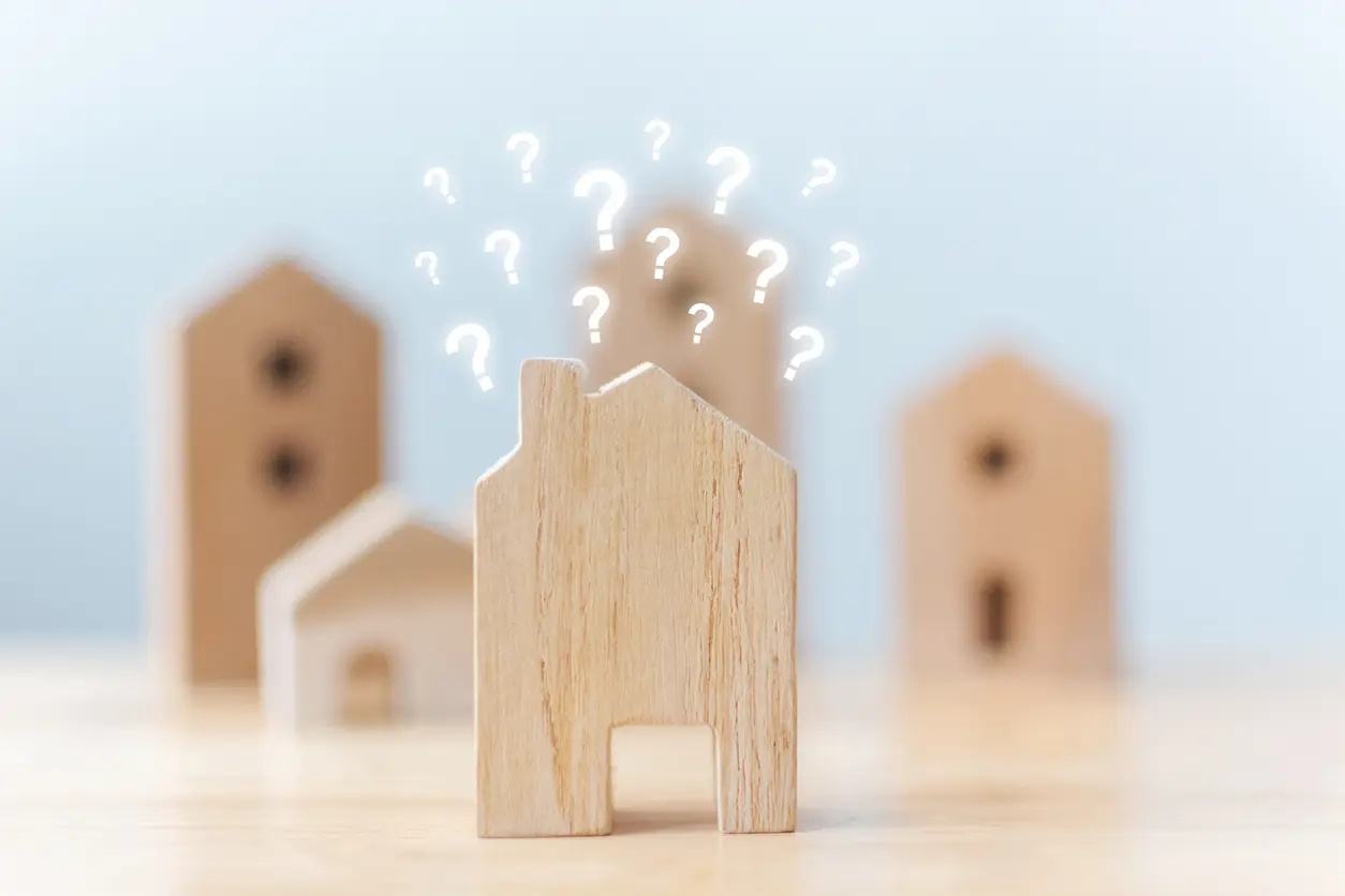 A wooden house adorned with various question marks, symbolizing curiosity about a rental home. 