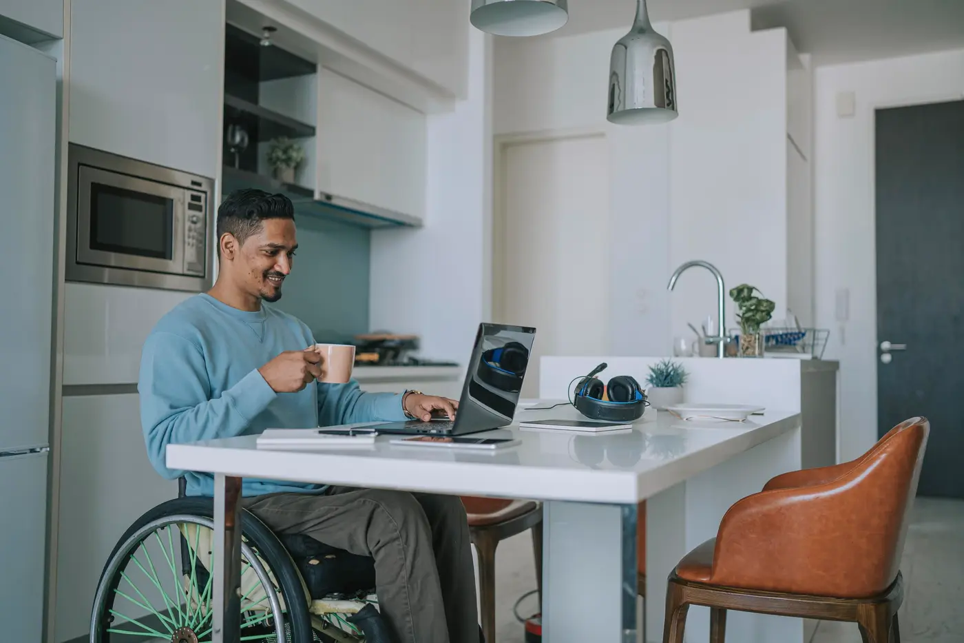 Man with disability working at home using laptop and smiling.