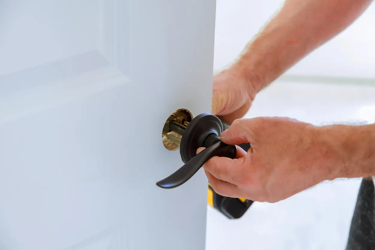 Close up of person’s hand installing a door lock. 