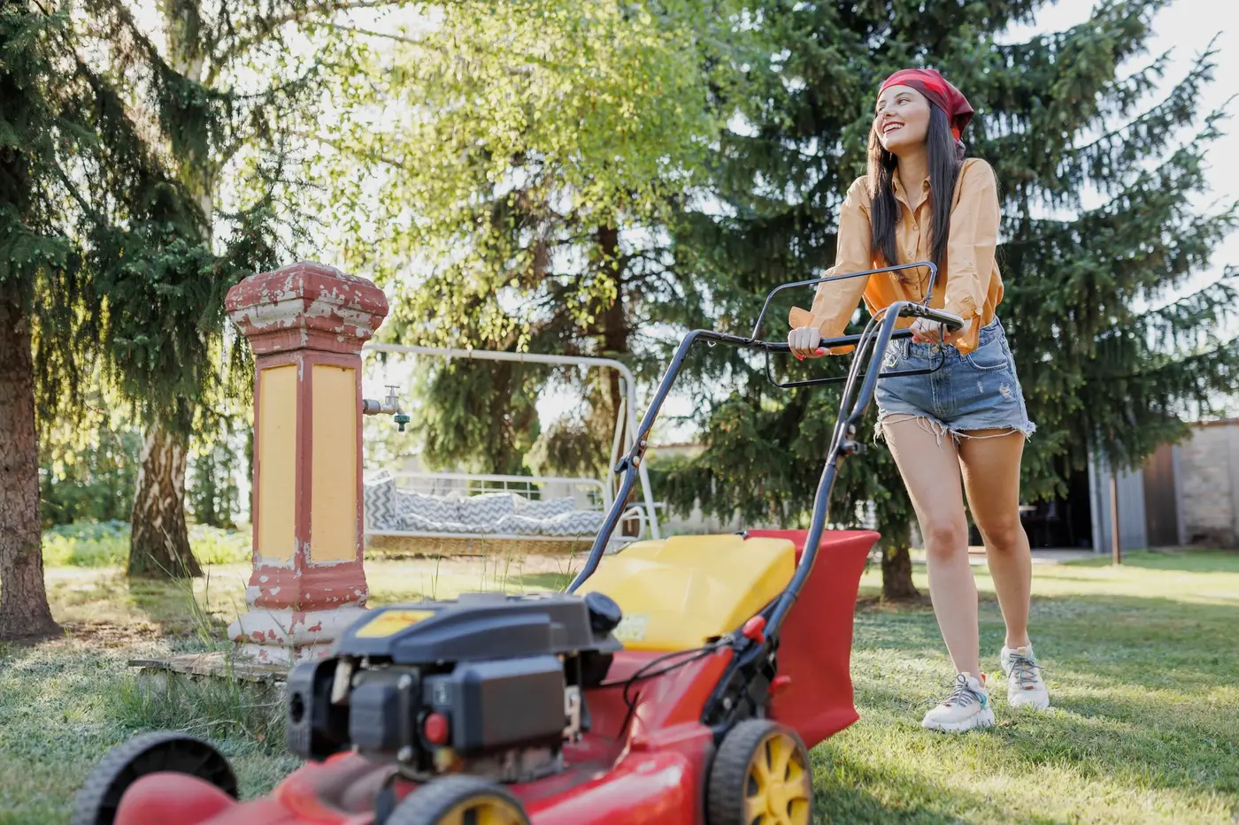 A woman performs summer maintenance by mowing her lawn.