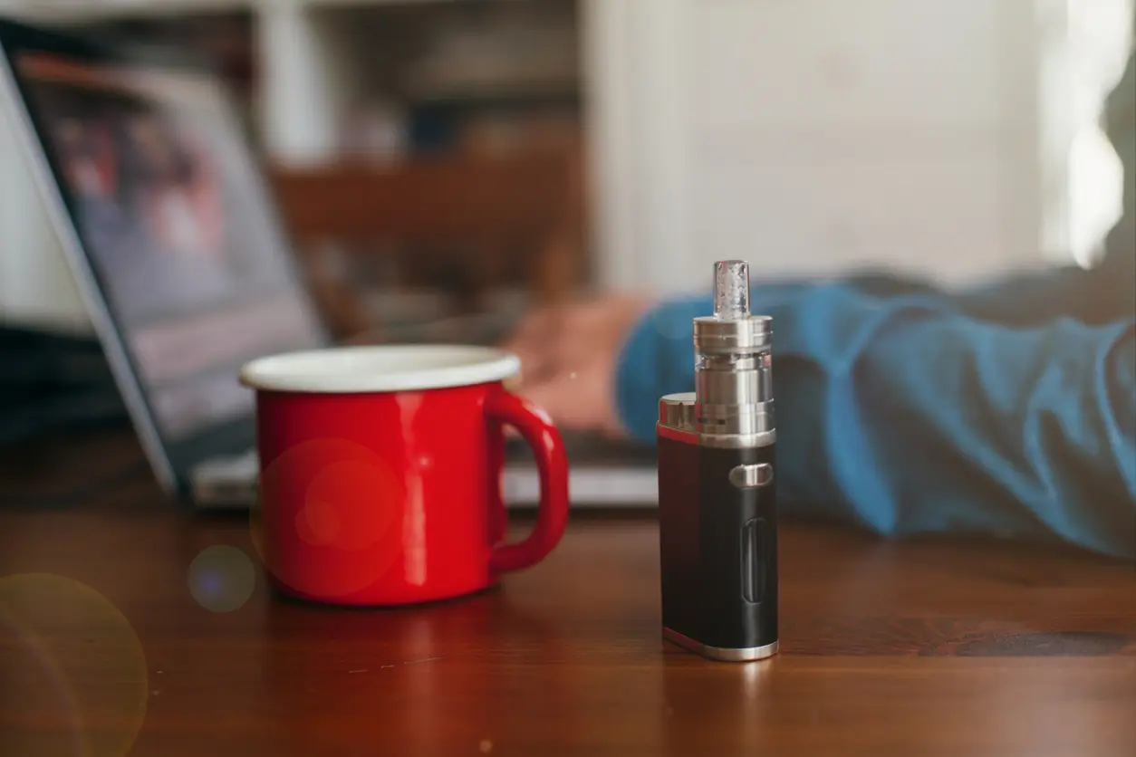 Vaping Device Standing Next to a Mug of Hot Coffee