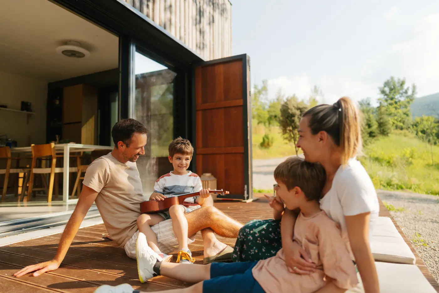 Photo of a family with two young children lounging on the front deck of their vacation house.