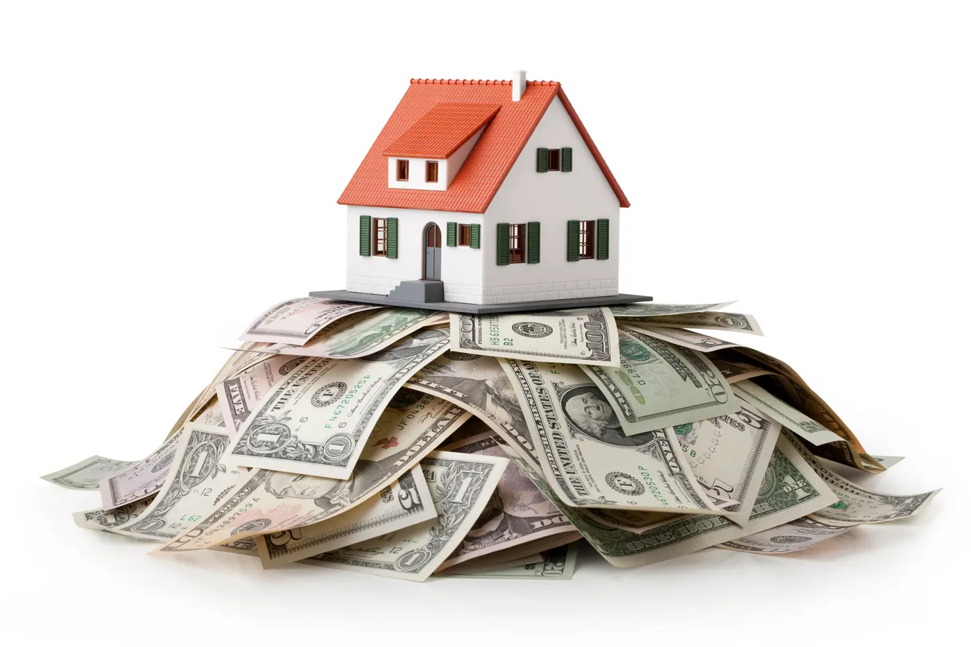 Miniature model house standing on a heap of dollar bills.