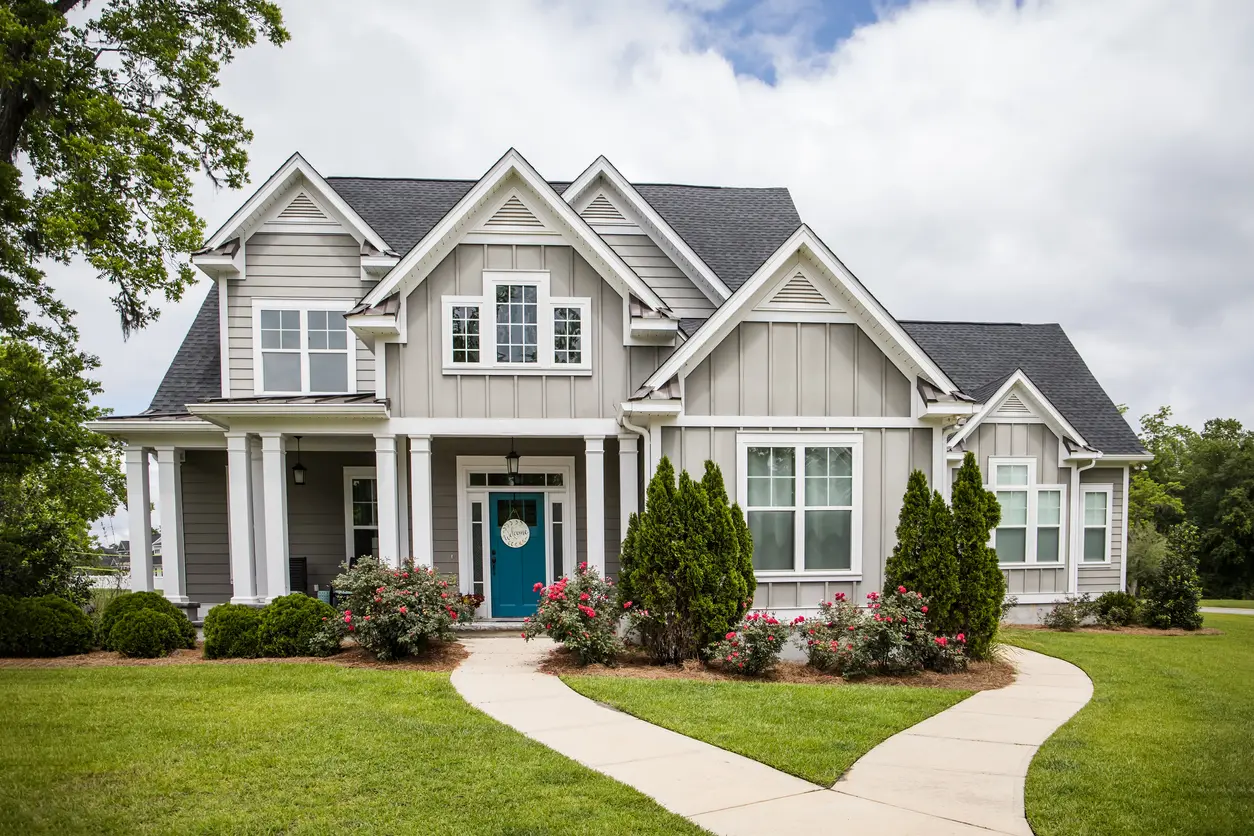 This is a single family home that is new construction cottage style house with hardy board and a partial metal roof. It is grey with a teal door and there is great curb appeal. The house has a double front entrance.