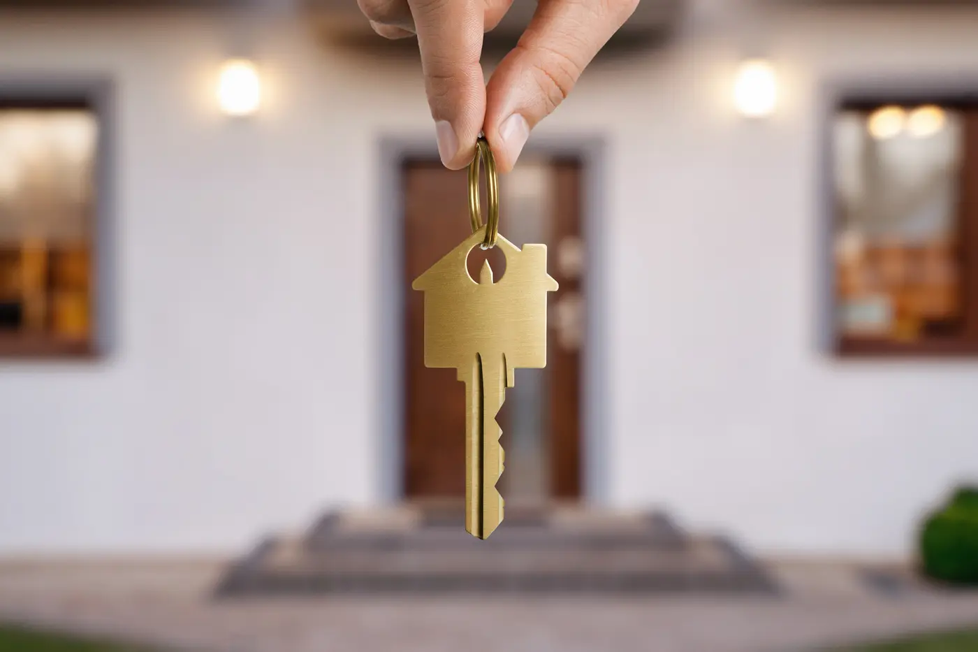 Close up of human hand holding gold key over the house door