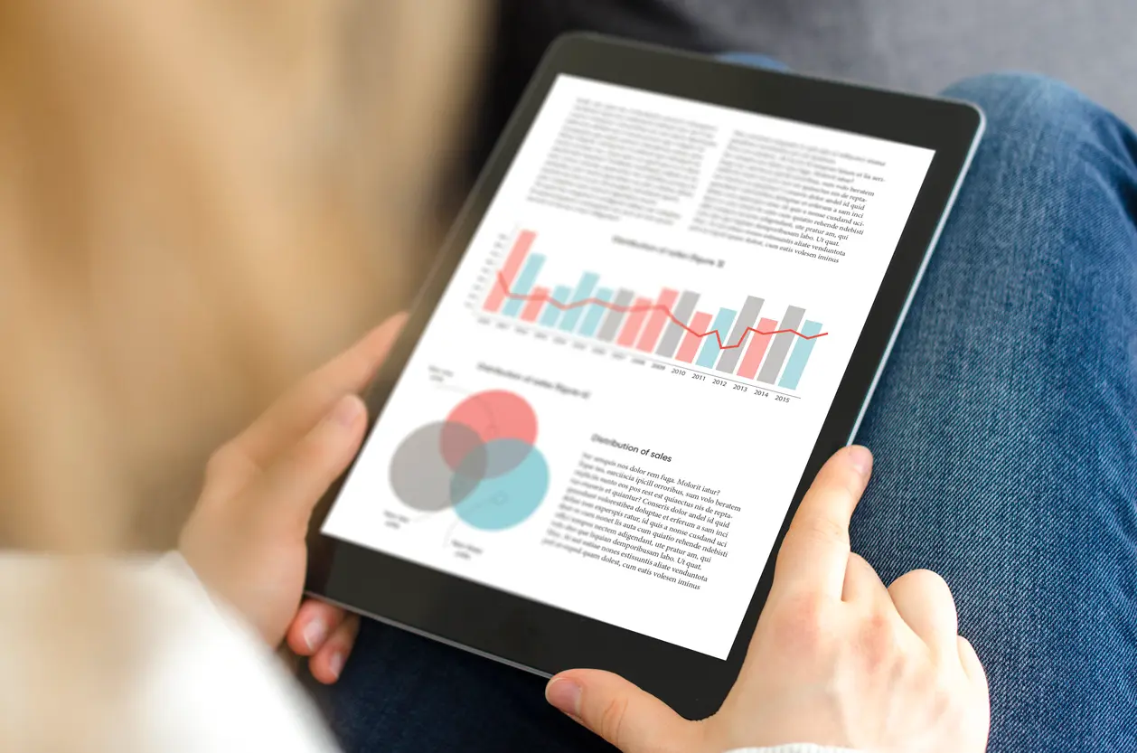 Person holding a tablet, on the device monitor visible are sales statistics and text.