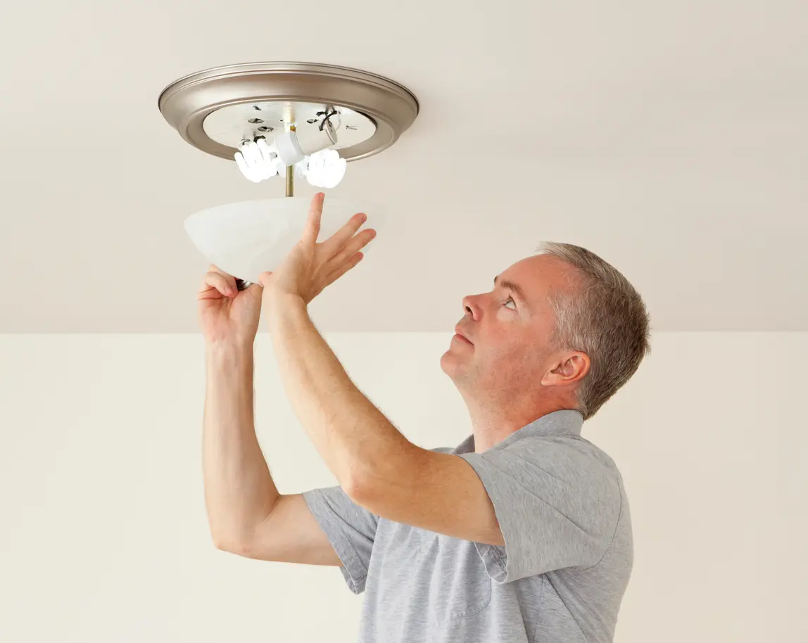 Lexington Park Property Manager Placing Energy Efficient Lightbulbs in a Fixture