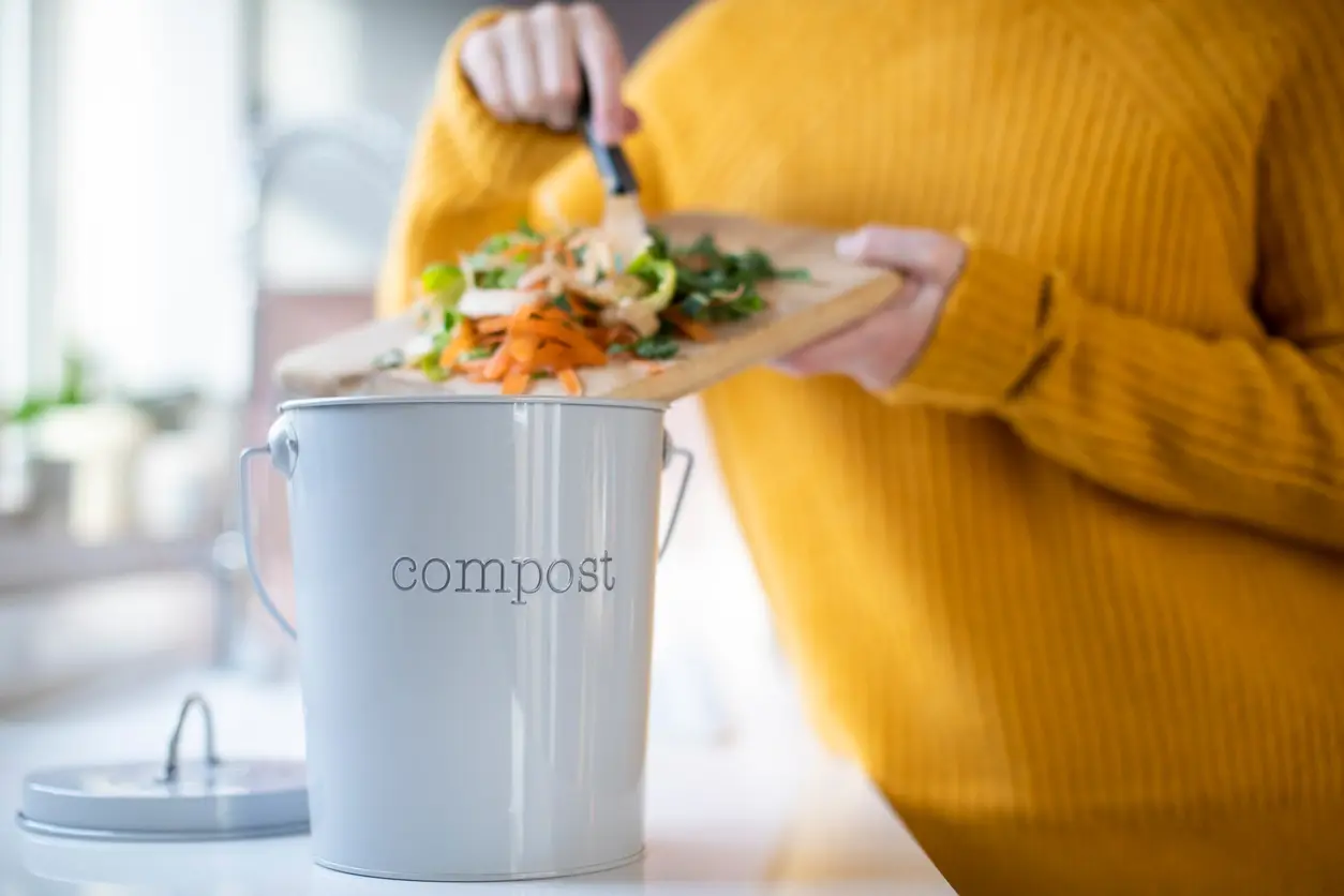 A Lusby Renter Putting Veggies Scraps in a Compost Bucket